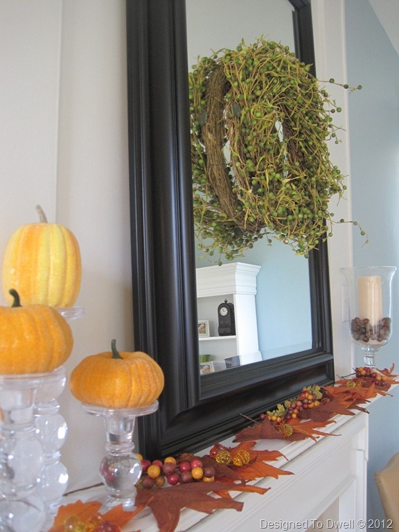 simple fall mantel decor with a mirror with a greenery wreath, fall leaves and acorns, faux pumpkins and candles