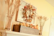 a rustic fall mantel with wheat arrangements, a faux leaf and berry wreath and a wooden box with faux pumpkins