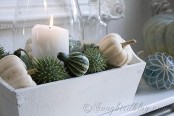 a neutral fall mantel with candles, a white wooden box and fresh pumpkins and gourds is a cute and beautiful fall decor idea