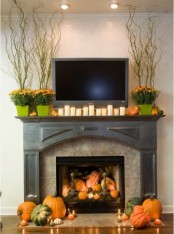 modern fall styling with bright fall blooms in planters, candles and fake pumpkins on the mantel and in the fireplace