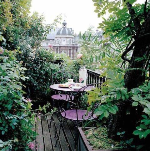 a super delicate small terrace with lots of greenery, a purple round table and a couple of chairs plus amazing views of the city