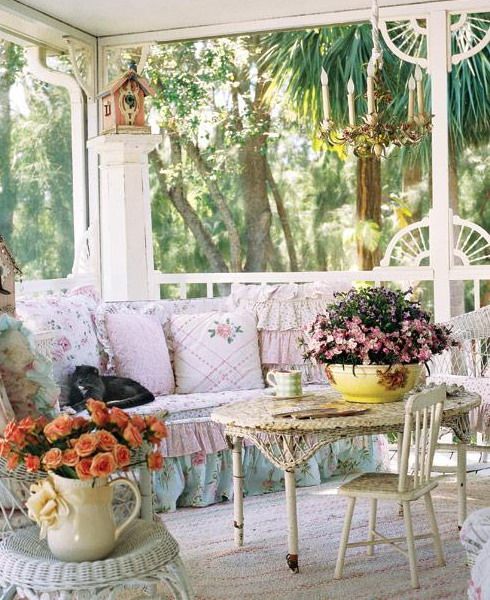 a chic vintage screen patio with white forged furniture, pastel floral upholstery and pillows, potted blooms and greenery is a lovely nook to relax here