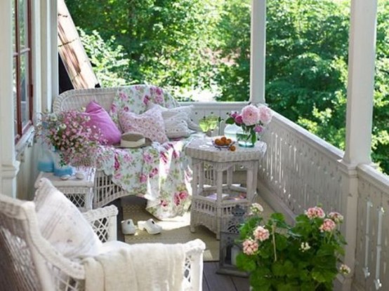 a vintage feminine patio with white wicker furniture, pastel textiles, pillows and blankets, lanterns and potted blooms is sweet and cute