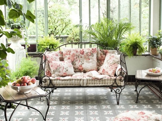 a beautiful neutral feminine terrace with a tiled floor, refined forged furniture with floral upholstery, lots of potted greenery is a gorgeous and sophisticated space