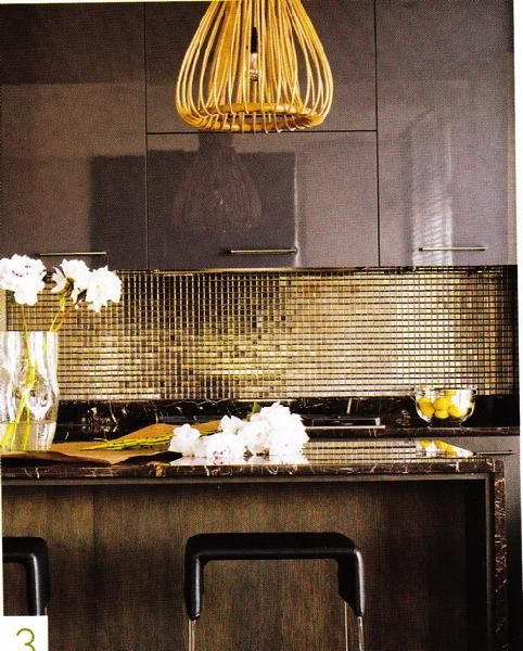a moody glam kitchen with dark cabinetry, a shiny gold tile backsplash, a chandelier and black marble countertops