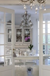 a glam shabby chic kitchen with a crystal chandelier, a vintage buffet, vintage dining furniture and some faux fur