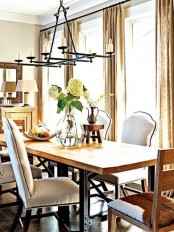 a neutral dining room with grey walls, a wooden table and neutral upholstered chairs, a chic chandelier