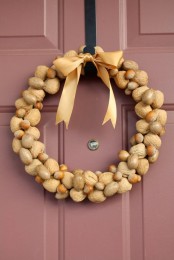 a natural and cool fall wreath made of walnuts and hazelnuts topped with a beige ribbon bow is a gorgeous idea for the fall