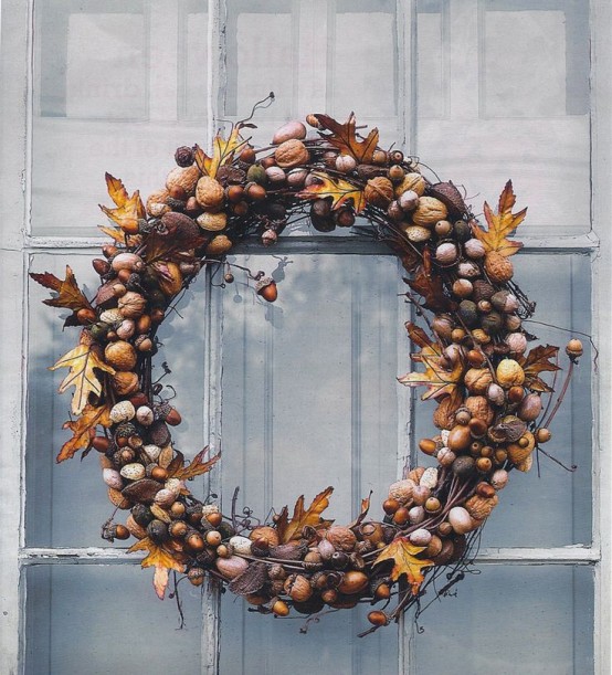 a relaxed rustic and woodland fall wreath covered with nuts of various kinds, acorns and natural fall leaves plus berries