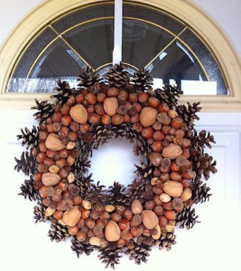 a rustic and woodland fall wreath covered with nuts, acorns and pinecones on top looks spectacular, cool and bold
