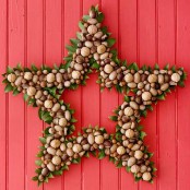 a star-shaped wreath made of nuts and acorns, with some greenery is a lovely decor idea with a catchy shape and a lovely look
