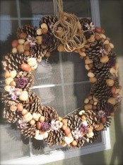 a rustic fall wreath made of pinecones, nuts, dried blooms and some twine on top is a cool idea for a woodland or rustic space