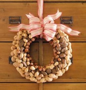 an organic fall wreath covered with nuts and topped with a large pink and white ribbon bow is a cool and fun solution for the fall