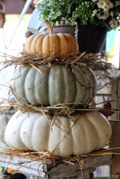 a stack of heirloom pumpkins with hay is a gorgeous rustic decoration for indoors or outdoors