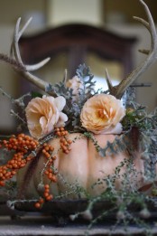 a blush pumpkin with blush blooms, greenery, berries and antlers for a chic Thanksgiving centerpiece