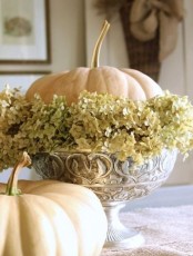a vintage bowl with dried hydrangeas and a single white pumpkin is a stylish vintage-inspired centerpiece or decoration
