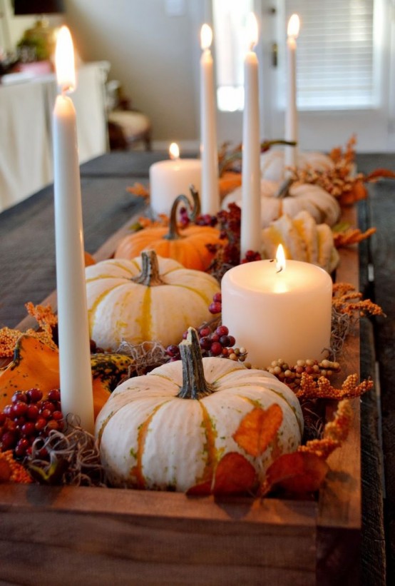 a wooden box with hay, berries, pumpkins, gourds and tall and pillar candles is a stylish rustic centerpiece for Thanksgiving