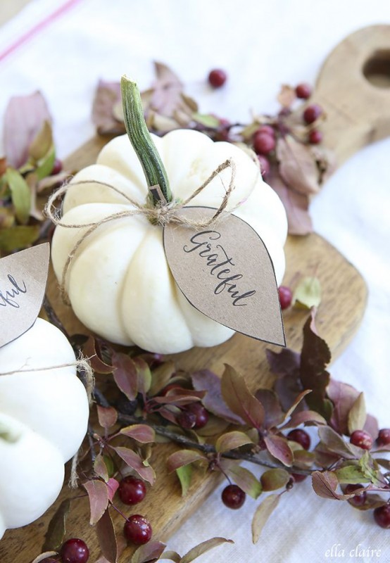 a cutting board with cherries, greenery and white pumpkins with tags for a Thanksgiving centerpiece