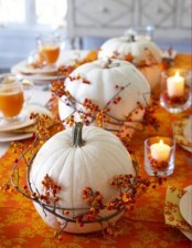 white pumpkins wrapped with berry branches and with candles are a nice Thanksgiving centerpiece or decoration