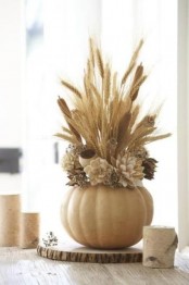 a neutral pumpkin with dried flowers, herbs and some pampas grass on a wood slice for Thanksgiving
