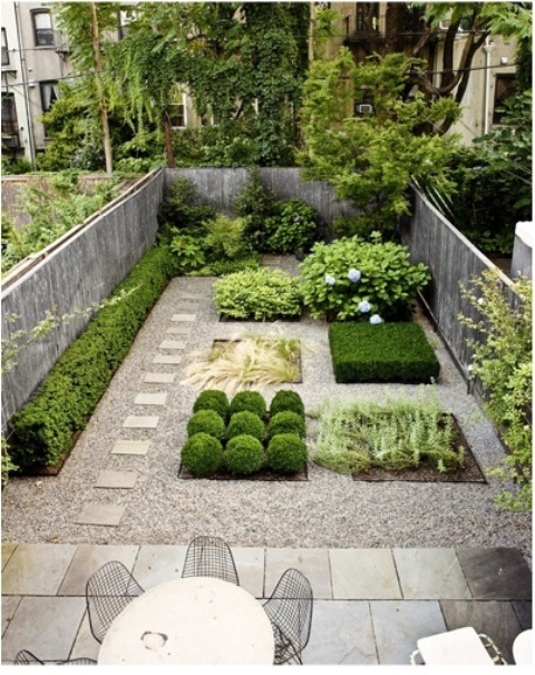 a minimalist townhouse garden with stone tiles, pebbles, stylish plants with no flower beds and a dining set