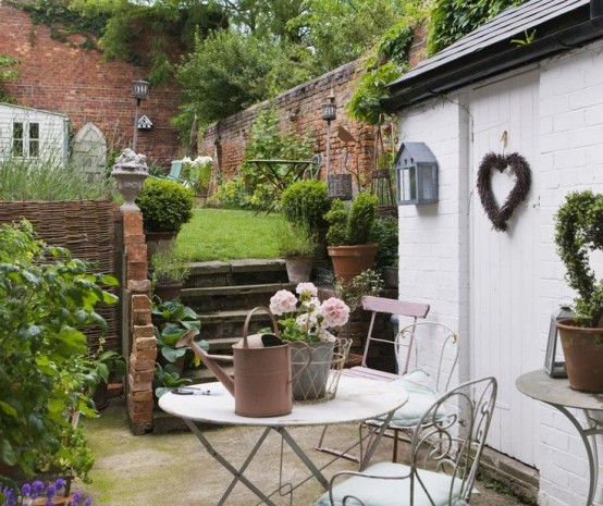 a cozy rustic meets vintage garden space with vintage garden furniture, a cool lawn and potted greenery