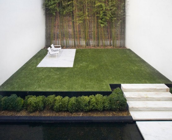 a minimalist garden space with stone steps, a manicured lawn, planted greenery and bamboo and minimalist furniture