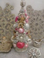 a vintage tabletop Christmas tree composed of vintage ornaments in silver and bright colors plus brooches