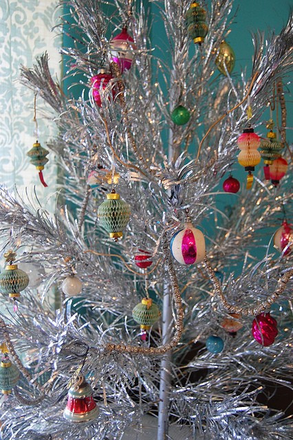 a vintage silver Christmas tree with colorful glass and paper ornaments is classics that will bring vintage charm to the space