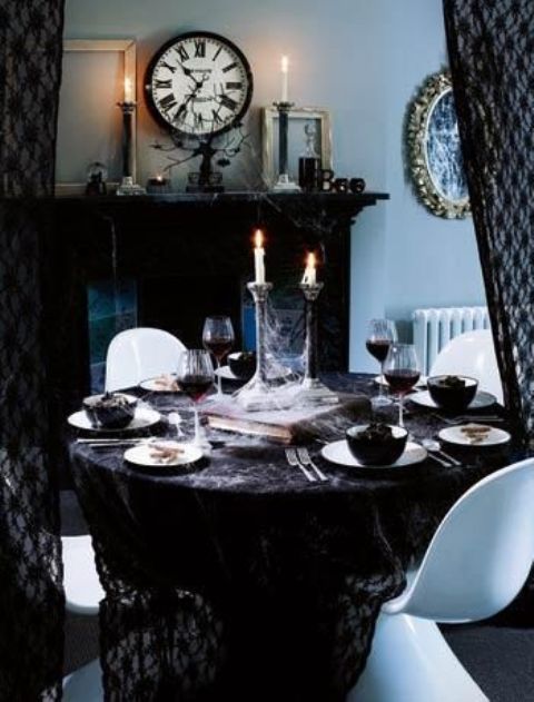 a refined vintage Halloween tablescape with a black tablecloth, white porcelain and black bowls, haunted candleholders with candles is amazing and chic