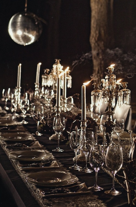 a refined haunted tablescape with a black tablecloth, white lace runners, white candleholders and candles, refined candelabras, dried blooms and greenery