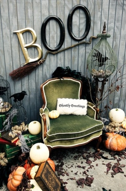 a vintage Halloween nook with a green vintage chair, stacks of vintage books, pumpkins, a broom and some letters