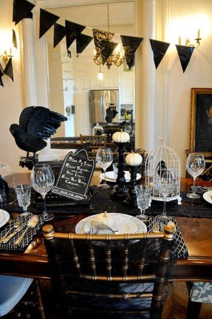 vintage Halloween decor with a black bunting, black linens, blackbirds, white pumpkins and elegant cutlery and glasses
