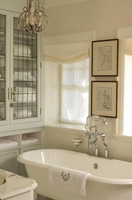 a creamy and off-white bathroom with artworks in dark frames for a chic space