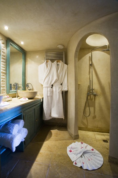a cathcy taupe and teal bathroom with an arched shower space and a bold vanity with storage