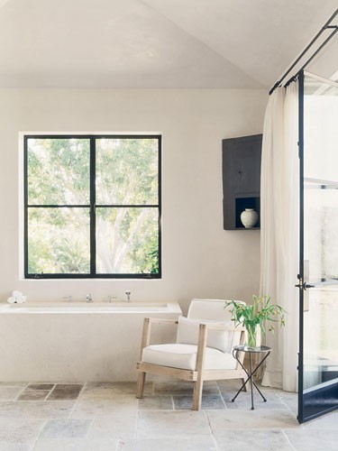 a creamy and beige bathroom with dark touches and adorable vintage charm plus a greenery arrangement