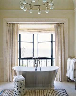 a beige and creamy bathroom with a large window that brigns much natural light inside