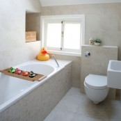 a light beige bathroom clad with tiles, with white appliances and colorful and whimsy accessories