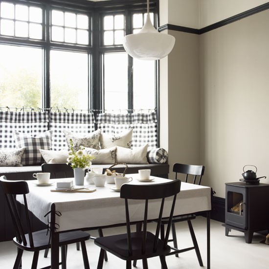 a cozy and catchy black and white dining space with a bay window, a windowsill seat, black furniture and white accessories