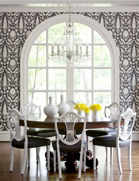 a dining room with black and white wallpaper, an arched window, a stained round table and black and white chairs