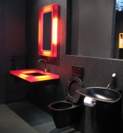a modern total black bathroom with a large mirror, black appliances a lit up mirror and a vanity to add color and interest