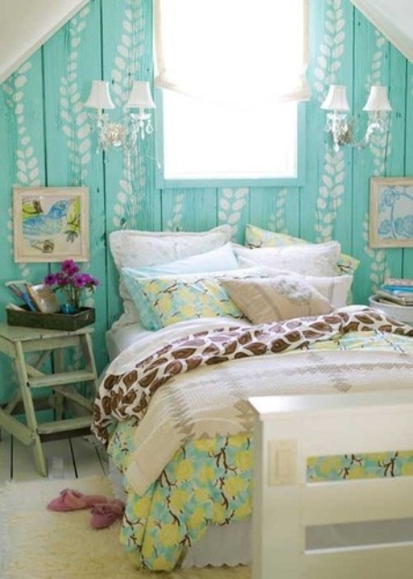 a small attic bedroom with a turquoise accent wall, a bed with printed colorful bedding, mismatching nightstands and elegant sconces