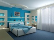a turquoise and white bedroom with built-in storage units, a white upholstered bed and turquoise bedding, a mirror and a desk and white curtains