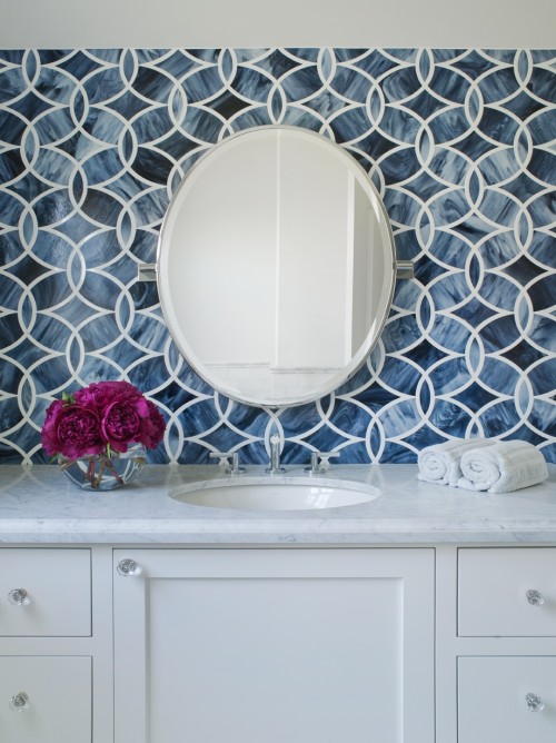 navy mosaic tiles, a white vanity and a round mirror for a stylish bathroom sink space