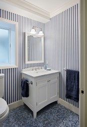 striped navy and white wallpaper paired with navy penny tiles on the floor make up a chic ambience