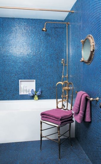 bright blue penny tiles paired with brass fixtures and a porthole create a cool bold look with a nautical feel