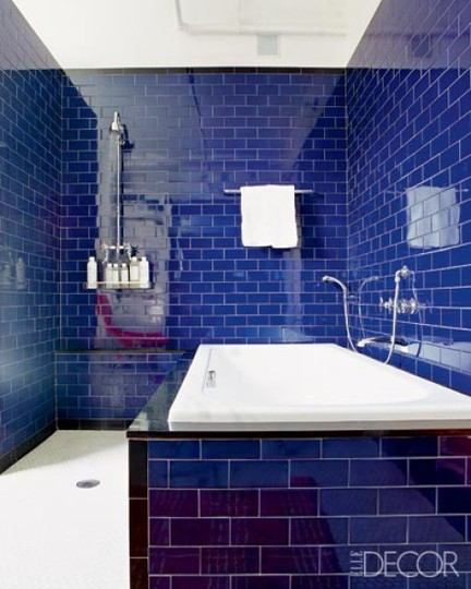 a very bright and glossy navy tile bathroom accented with white grout plus metallic fixtures