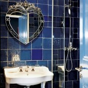 mismatching blue and navy tiles on the wall and a refined heart-shaped mirror for a luxurious space