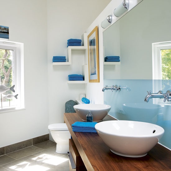 a sleek light blue half wall and bright blue towels for a contemporary bathroom