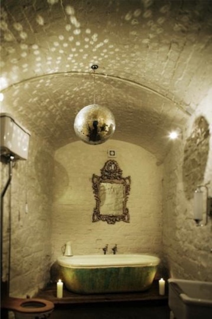 a unique white bathroom with a green shabby chic bathtub, an ornate mirror, a sparkling lamp and candles